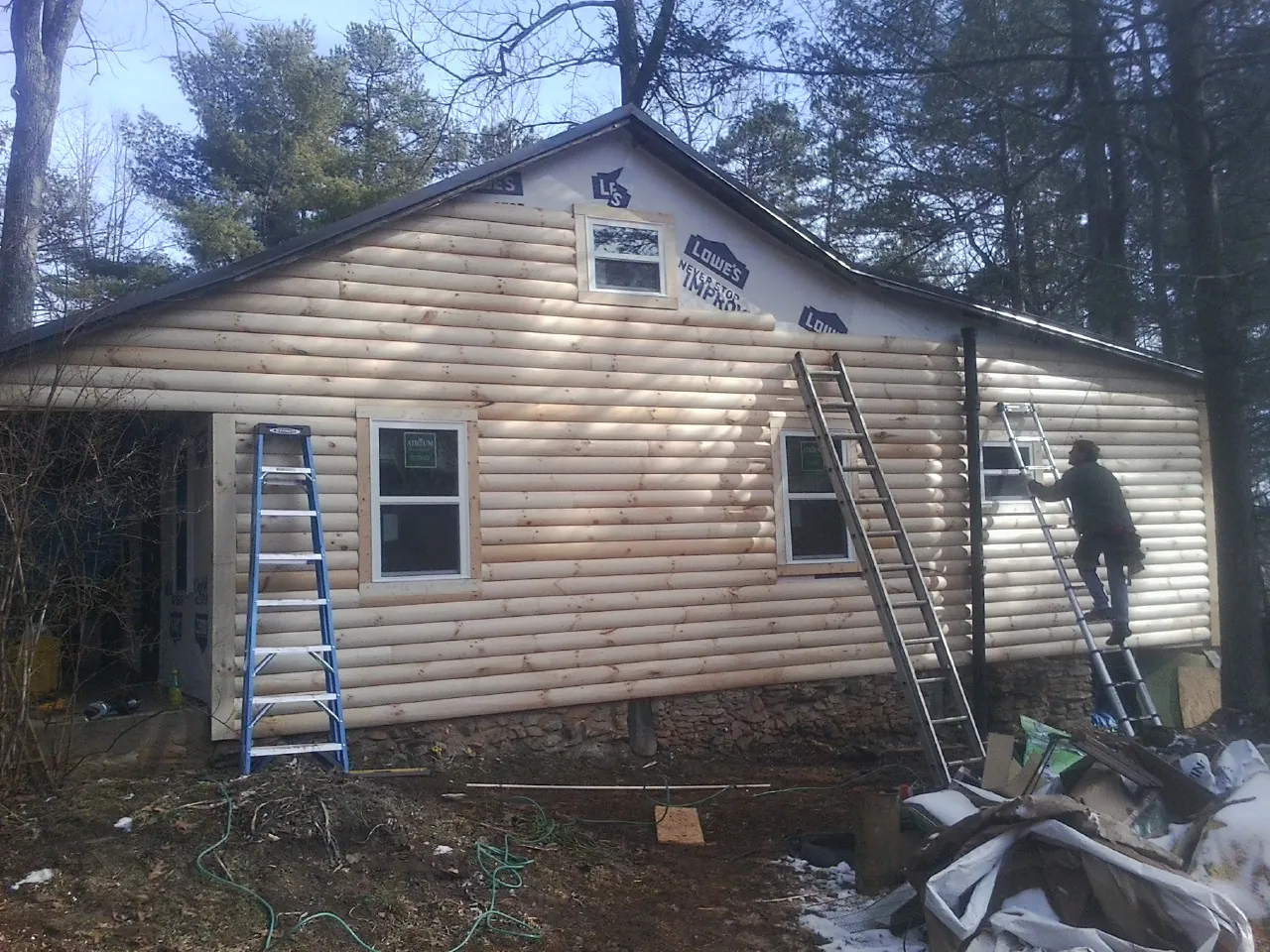 Ladders set against fresh log siding during an exterior remodel in Polk
