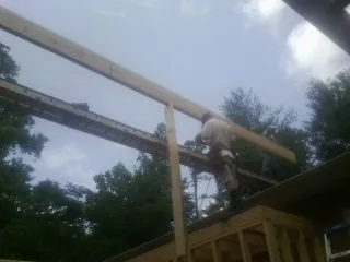 Carpenter setting a ridge beam over a new addition frame — Ice Dam Removal by Roofing Brothers in Polk