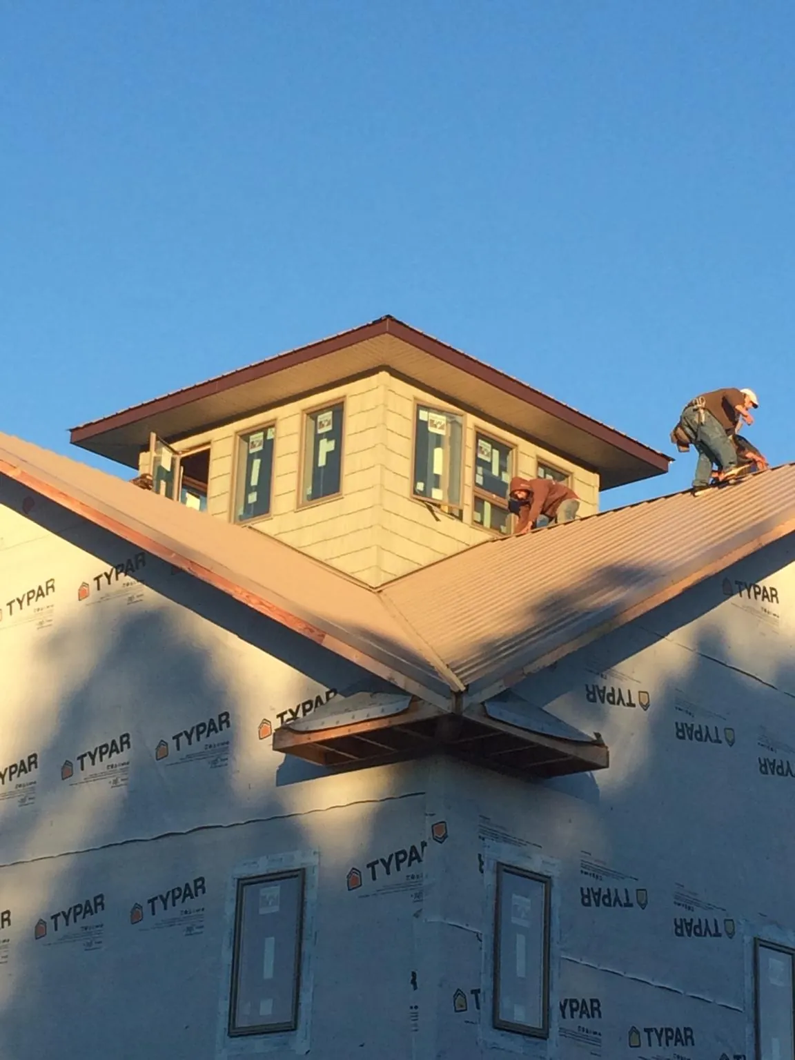 Roofers working around a rooftop cupola on a new metal roof at sunset — Roof Waterproofing in Polk by Roofing Brothers